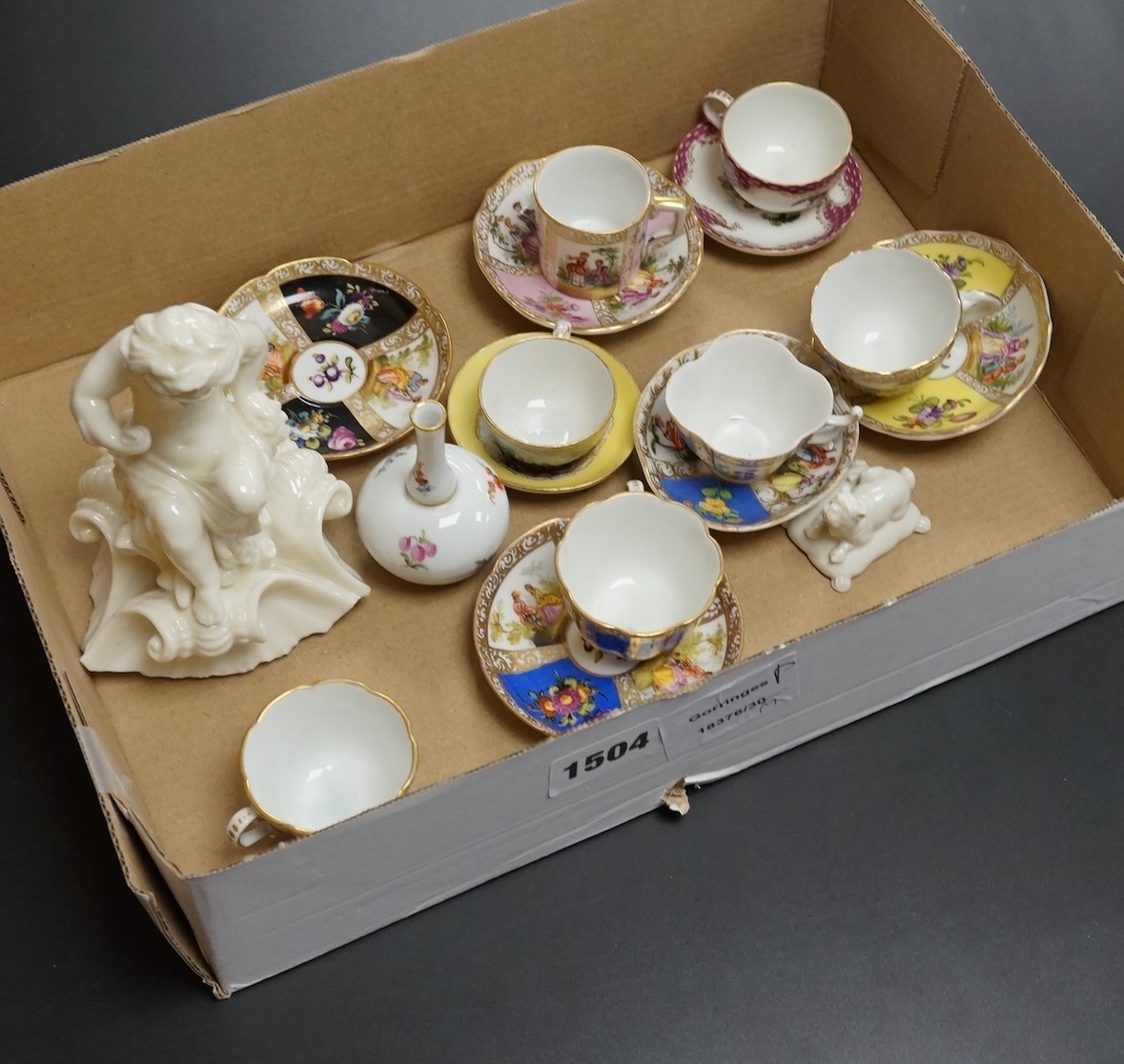 A group of 19th/20th century German porcelain, comprising a Nymphenburg pug, seven Dresden miniature cups and saucers and a Meissen bottle, largest 13cm high